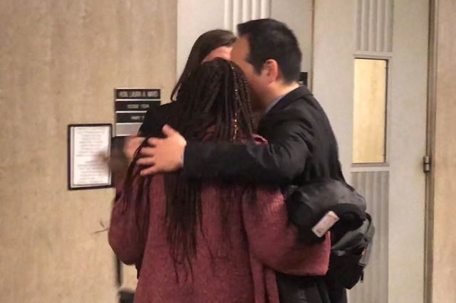 A photograph of the Kims and Lee's sister embracing outside the courtroom.